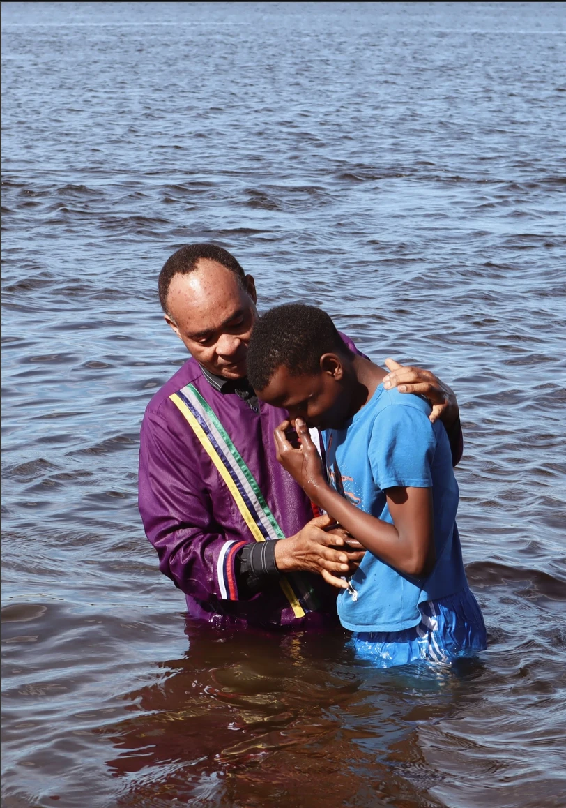 A pastor baptising a young person in open water