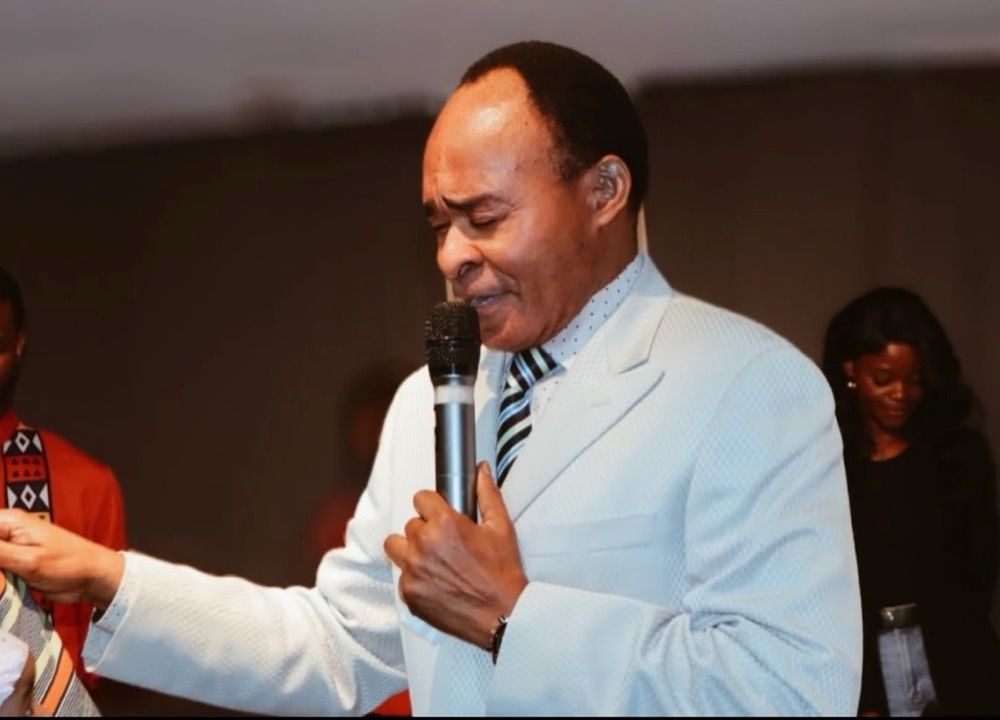 Pastor Mlongecha praying with a microphone